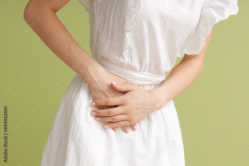 Young woman suffering from severe abdominal pain on green background, closeup Young woman suffering from severe abdominal pain on green background, closeup