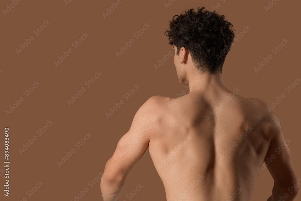 Fototapeta premium Muscular young man on brown background, back view