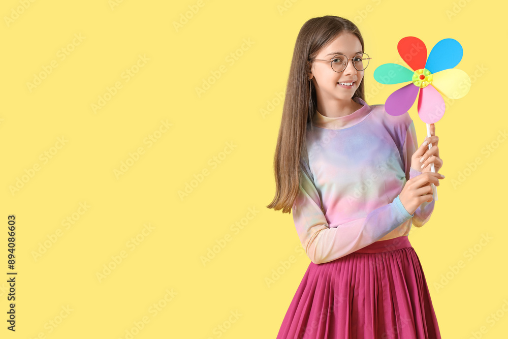 Happy teenage girl with toy windmill on yellow background Happy teenage girl with toy windmill on yellow background
