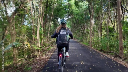 Female riding an electric bike through the scenic countryside part of a tourism cycle pathway