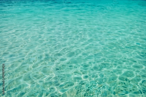 Turquoise sea water with gentle waves and a clear view of the sandy bottom, showcasing the purity and beauty of a tropical beach. Ideal for serene, summer, and travel visuals.