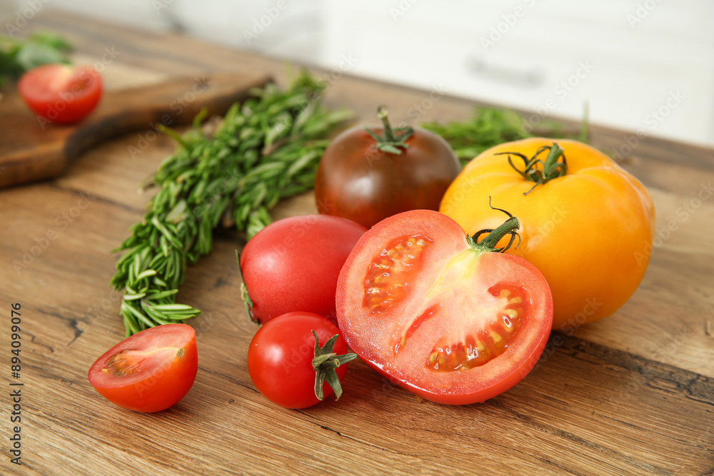 Different fresh tomatoes and rosemary on wooden table Different fresh tomatoes and rosemary on wooden table