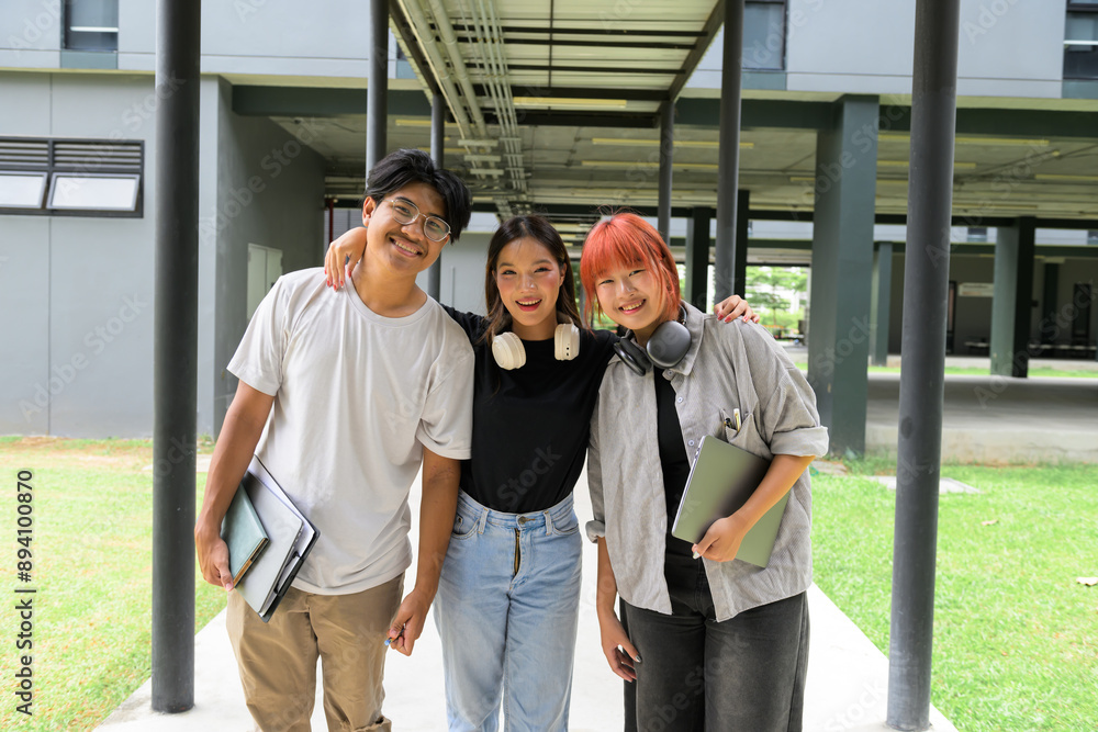 © Parichat - Group of Happy Students Standing Together Outdoors on Campus, Smiling and Holding Books and Laptops