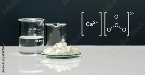 Calcium carbonate chip in chemical watch glass with molecular structure on white laboratory table. Side view