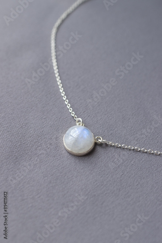Tableau sur toile Shiny silver chain with moonstone on gray textile backgound