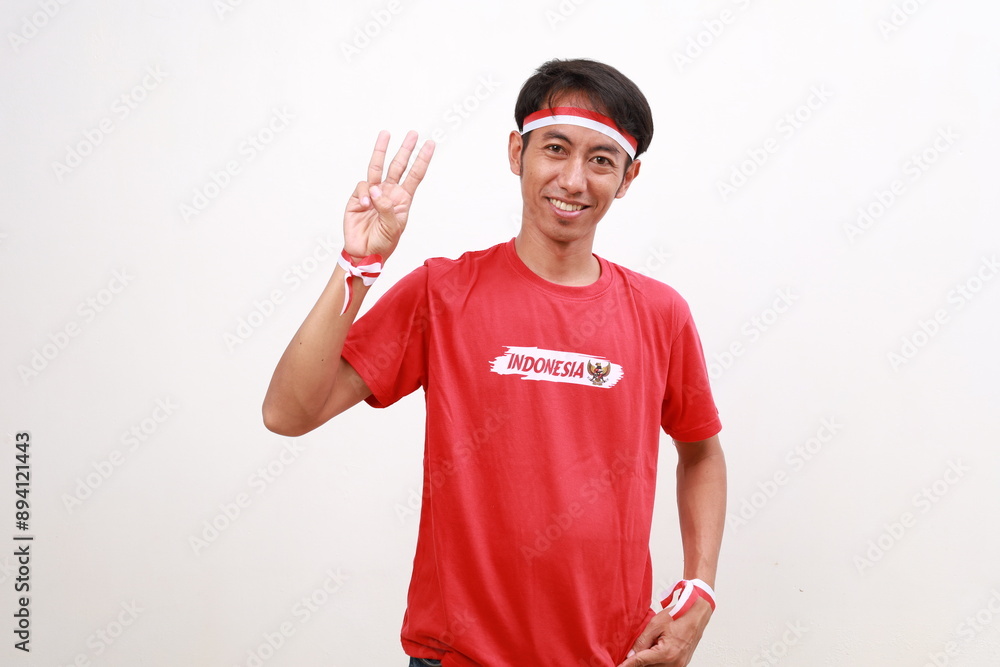 Asian young boy with red white ribbon for celebrating Indonesia independence day standing while showing three fingers Asian young boy with red white ribbon for celebrating Indonesia independence day standing while showing three fingers