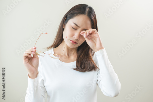 Canvas-taulu Eye problem concept, fatigue asian young woman tired eyes irritated rubbing, massage eye dry relief vision pain after work, eye strain, hand holding glasses, suffer bad blurry isolated on background