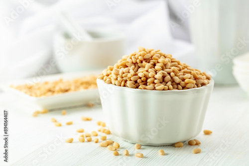 Pine nuts in white dish on a white background.