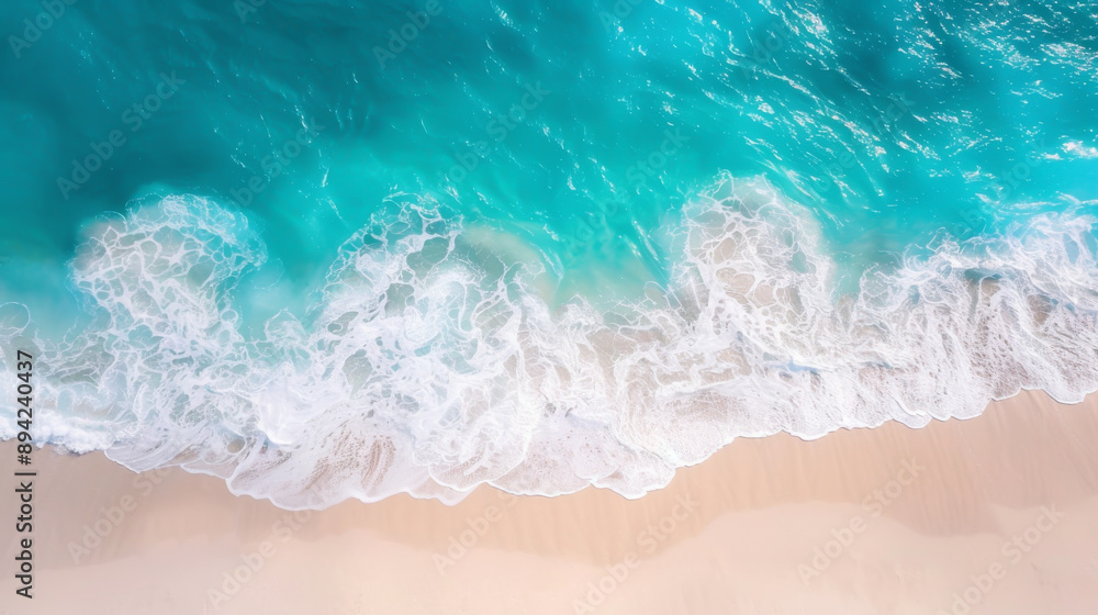 Obraz premium Aerial view of turquoise ocean waves gently crashing onto a pristine sandy beach, creating a serene and tranquil coastal scene.