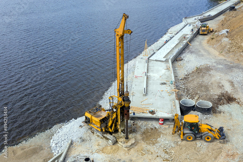 Pile driver at the construction of new embankment on the river bank