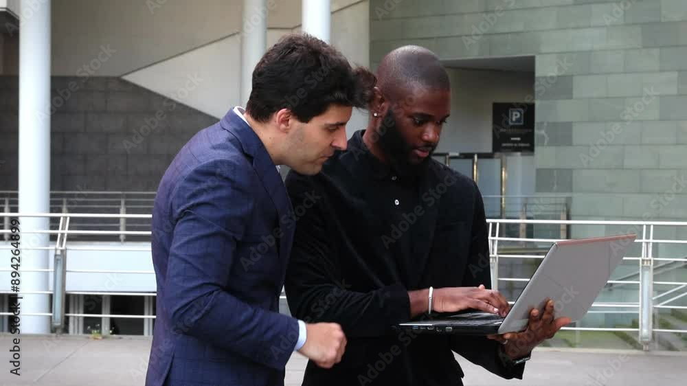 Multicultural businessmen reviewing company data on laptop in financial district Multicultural businessmen reviewing company data on laptop in financial district