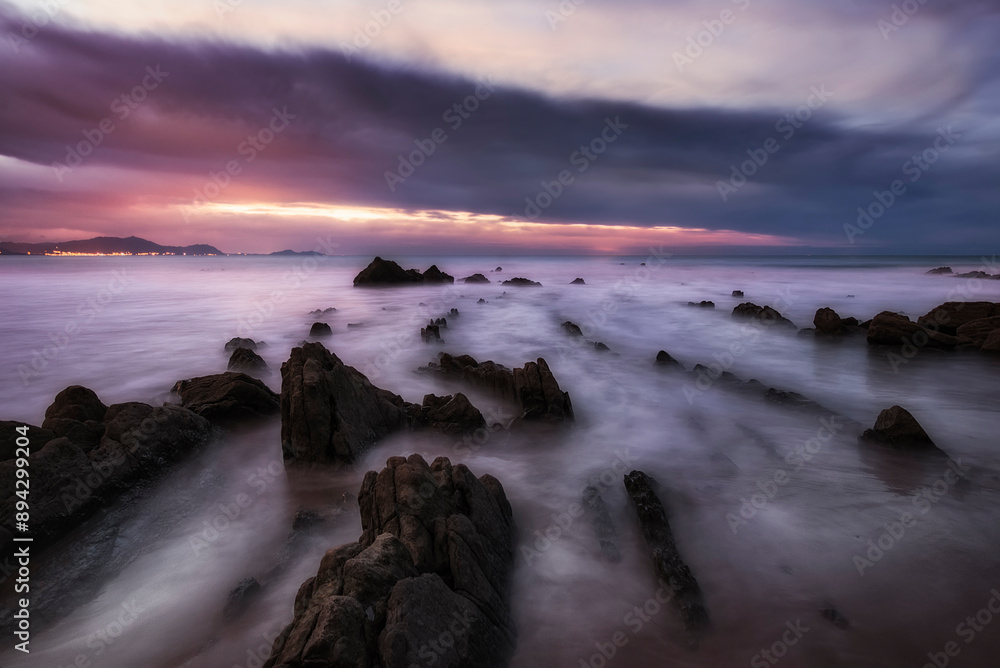 Sunset with clouds on Barrika beach with the tide between the flysch Sunset with clouds on Barrika beach with the tide between the flysch