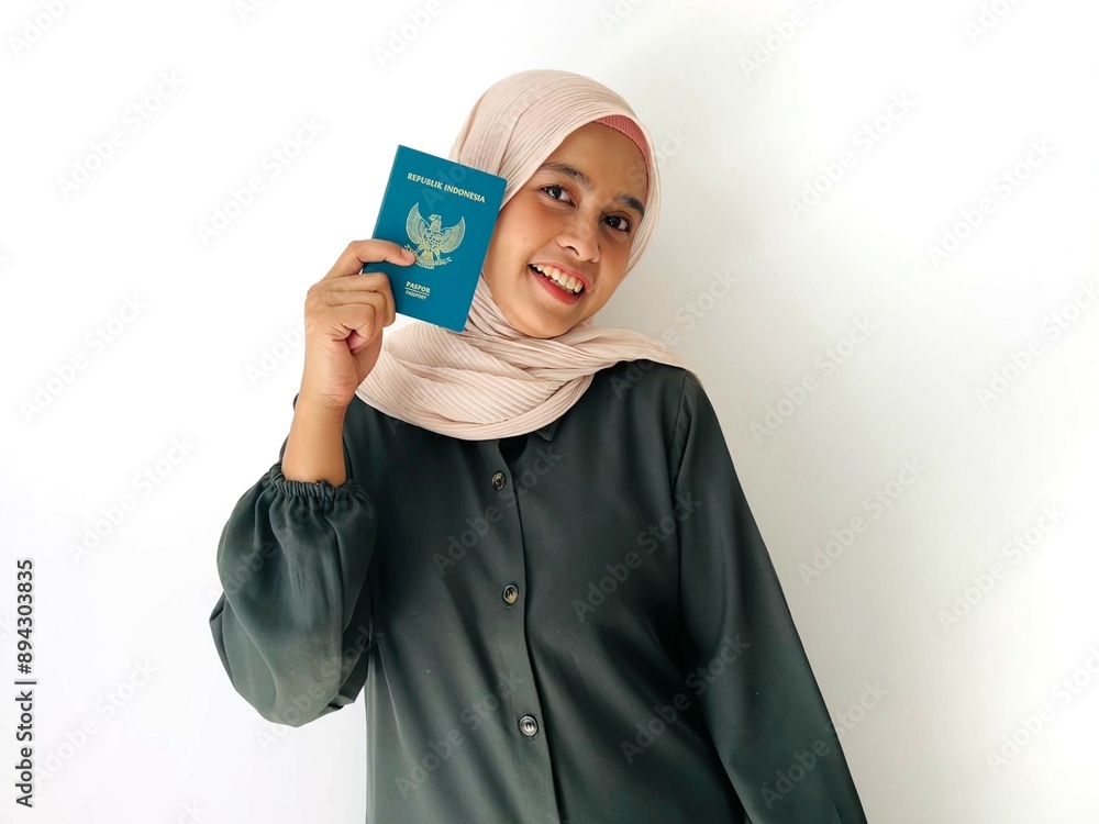 A standing woman with smiling face holding Indonesian passport isolated on white background. Successful visa application concept A standing woman with smiling face holding Indonesian passport isolated on white background. Successful visa application concept
