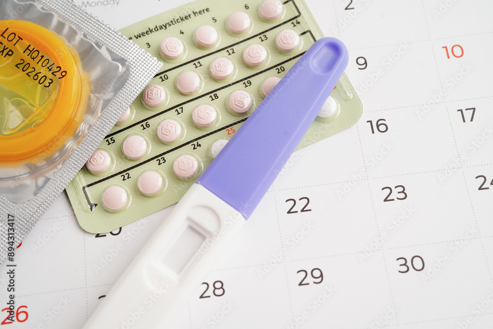 Pregnancy test with birth control pills and condom for female on calendar, ovulation day. Pregnancy test with birth control pills and condom for female on calendar, ovulation day.