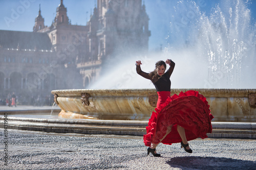 Young, beautiful, brunette woman in black shirt and red skirt, dancing flamenco in front of a beautiful fountain in Spain square in Seville. Flamenco concept, dance, art, typical Spanish.