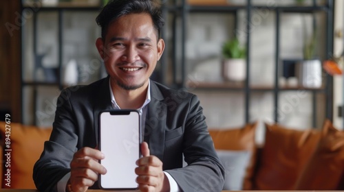 Smiling businessman showing blank smartphone screen.