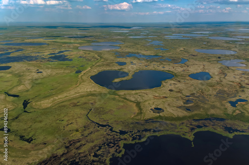 Arctic tundra in summer from an altitude of 2000 meters. Cloudy sky. Variety of colors and landscapes. The vastness of pristine nature. Shadow from the clouds