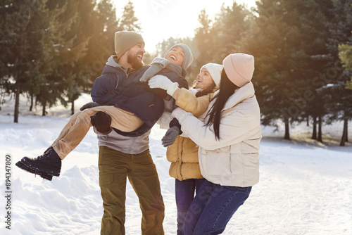 Fotografi Portrait of happy smiling young family with son and daughter standing outdoors enjoying time together in winter forest