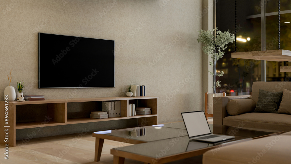 Contemporary living room at night featuring a laptop on a coffee table, a sofa, and a TV on the wall Contemporary living room at night featuring a laptop on a coffee table, a sofa, and a TV on the wall