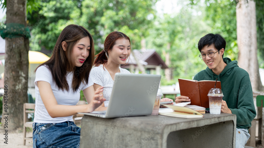 A group of positive Asian college students is working on a co-project together at a table in a park. A group of positive Asian college students is working on a co-project together at a table in a park.