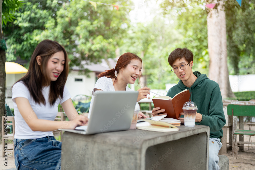 A group of positive Asian college students is working on a co-project together at a table in a park. A group of positive Asian college students is working on a co-project together at a table in a park.