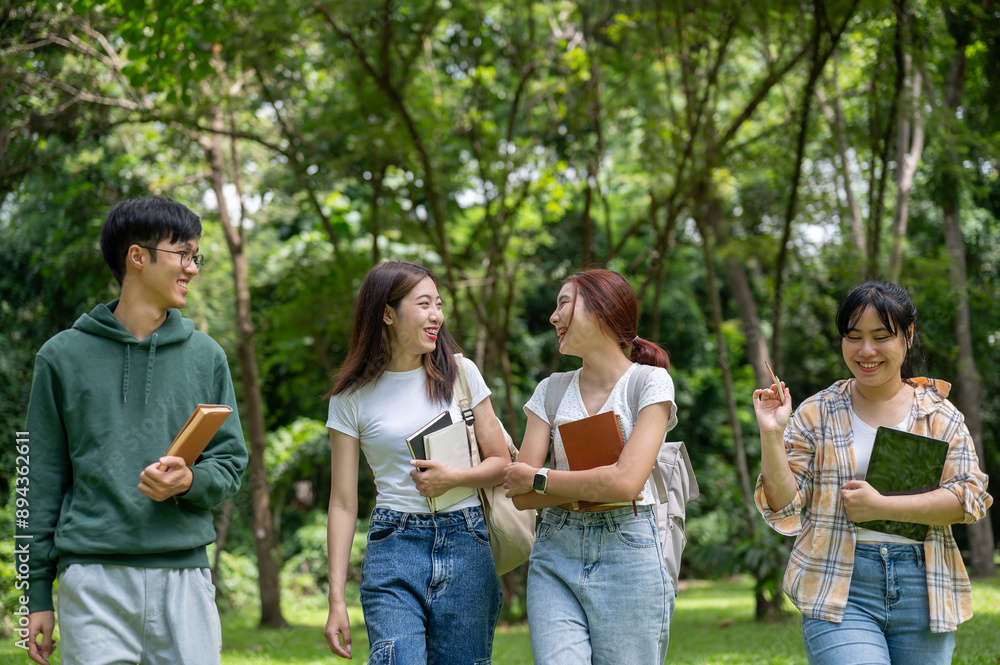 A group of cheerful Asian students are enjoying talking and laughing while walking in the park.
