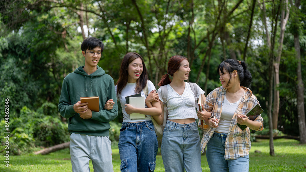 A group of cheerful young Asian students are laughing together while walking arm in arm in the park. A group of cheerful young Asian students are laughing together while walking arm in arm in the park.