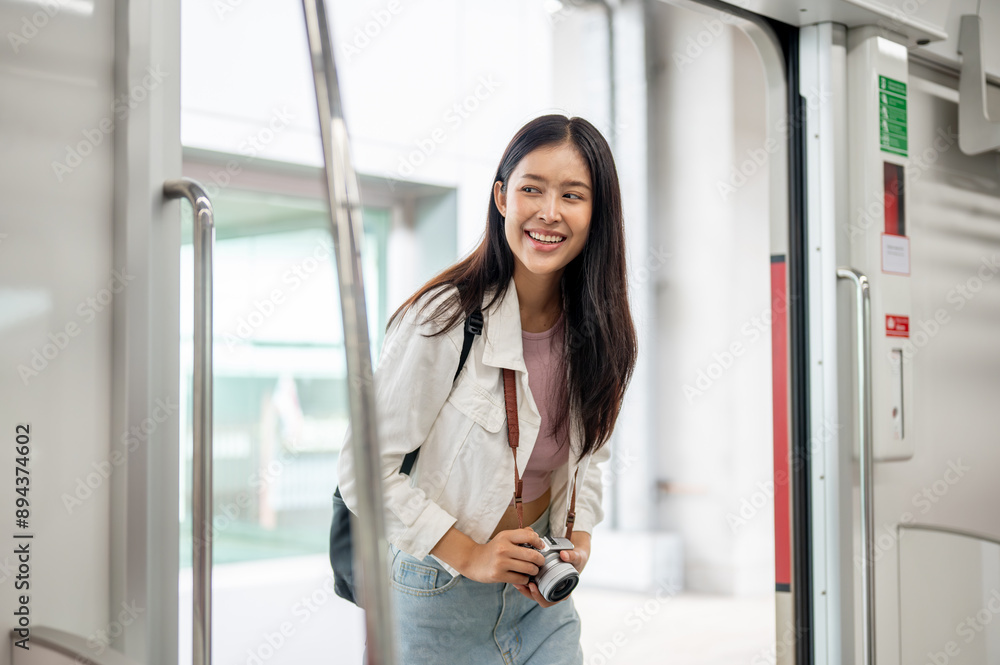 A beautiful, positive Asian female traveler with a backpack and a camera is getting on a sky train. A beautiful, positive Asian female traveler with a backpack and a camera is getting on a sky train.
