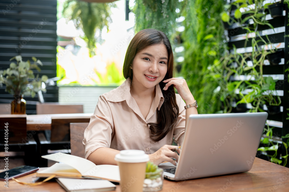 An attractive Asian businesswoman working remotely at a cafe, sitting outdoor with her laptop. An attractive Asian businesswoman working remotely at a cafe, sitting outdoor with her laptop.