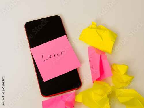 A smartphone on the table symbolizes procrastination and putting things off, reflecting a life put on hold and missed opportunities photo