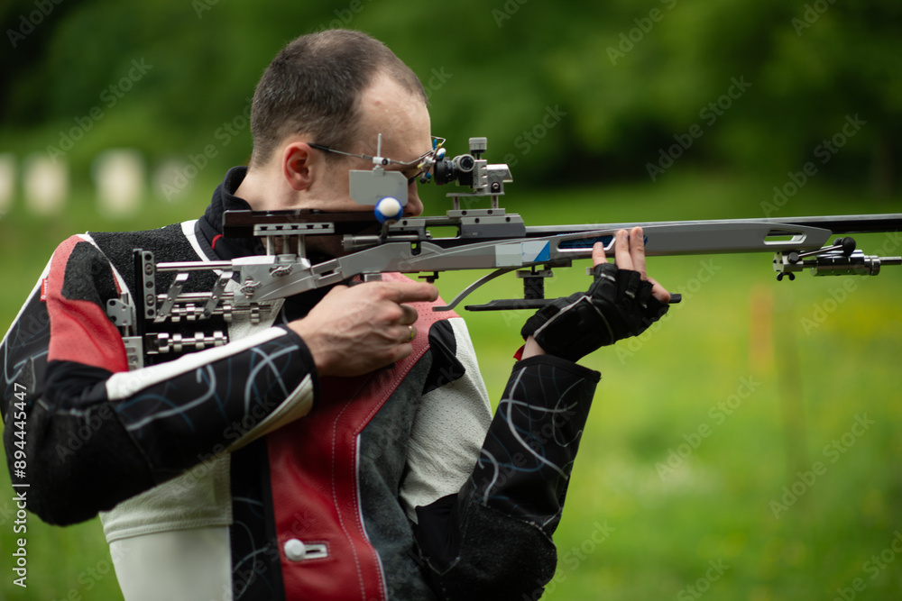 Fototapeta premium A skilled male athlete engages in free rifle training outdoors, demonstrating his expertise and precision in shooting, known for his dedication and focus in the open-air practice environment.