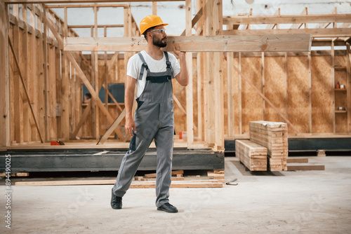 Obraz na plátně Going and carrying plank. Industrial worker in wooden warehouse