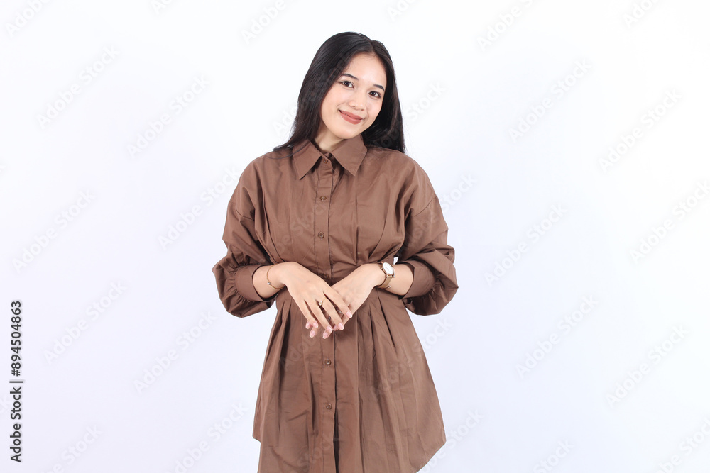 Happy Asian woman wearing brown clothes smiling and looking confident holding both hands above stomach isolated over white background Happy Asian woman wearing brown clothes smiling and looking confident holding both hands above stomach isolated over white background