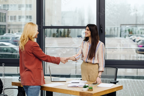 Foto Two hard-working women in an office, sealing a deal through a handshake