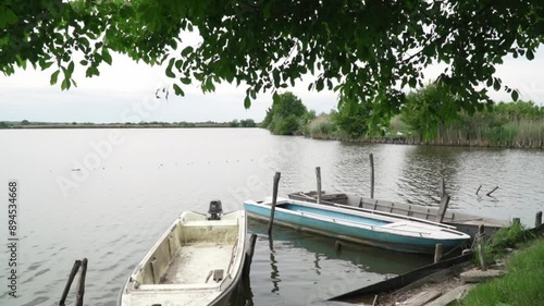 Weathered dirty small boats tied to a shore of large lake