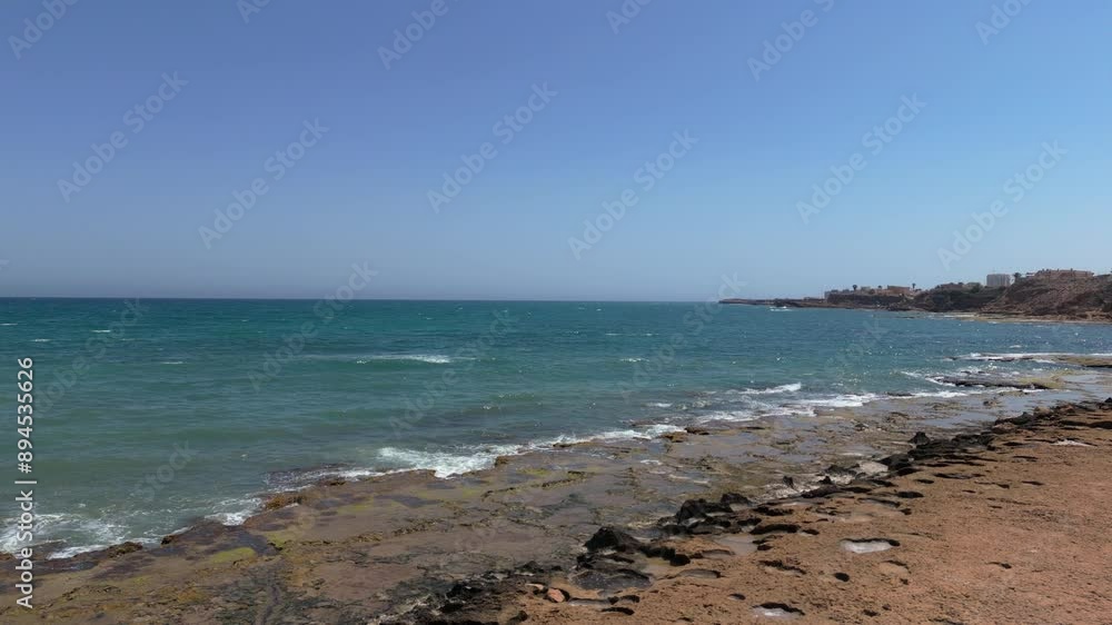A rocky shore with turquoise sea waves crashing against it, creating splashes of foam. Slow-motion recording, perfect for a vacation background. A rocky shore with turquoise sea waves crashing against it, creating splashes of foam. Slow-motion recording, perfect for a vacation background.