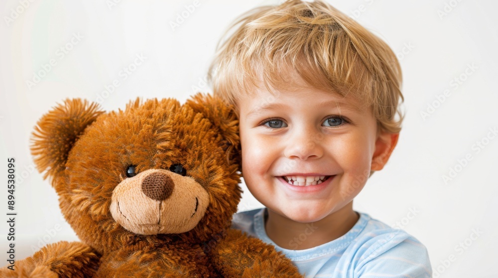 Smiling young boy holding a brown teddy bear, happy childhood moment, indoor setting with light background. Smiling young boy holding a brown teddy bear, happy childhood moment, indoor setting with light background.