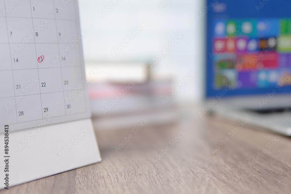 A desk calendar on a wooden table with a red circle marking a specific date. Appointment and reminder concept. A desk calendar on a wooden table with a red circle marking a specific date. Appointment and reminder concept.