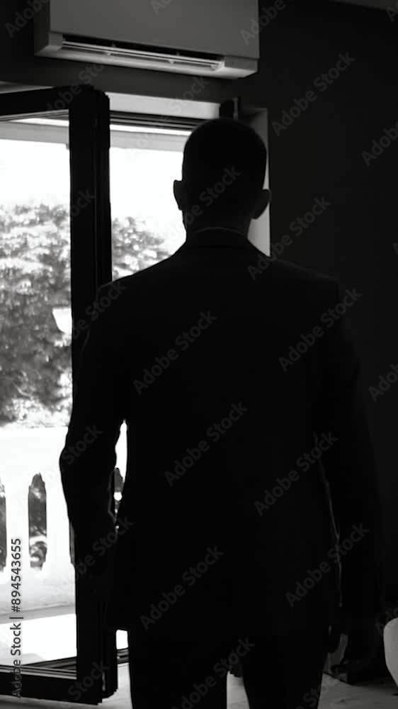 a dark black corridor and a room along which a man in a jacket and a classic suit walks, a businessman and a gentleman go to a business meeting in the office a dark black corridor and a room along which a man in a jacket and a classic suit walks, a businessman and a gentleman go to a business meeting in the office