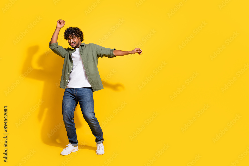 Fototapeta premium Portrait of young handsome carefree drunk student funny indian guy in khaki shirt dancing summer music vibes isolated on yellow color background