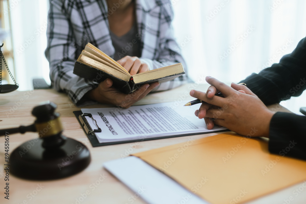 In a lawyer's office, a businessman consults an attorney for legal advice on a contract. The gavel symbolizes authority and justice. The lawyer explains the legislation and provides guidance on the ag In a lawyer's office, a businessman consults an attorney for legal advice on a contract. The gavel symbolizes authority and justice. The lawyer explains the legislation and provides guidance on the ag