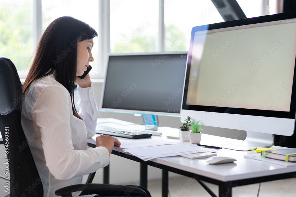 Businesswoman Talking On The Phone While Working On Computer In Modern Office Businesswoman Talking On The Phone While Working On Computer In Modern Office