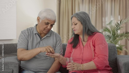 Old Indian wife giving medicine to her sick husband