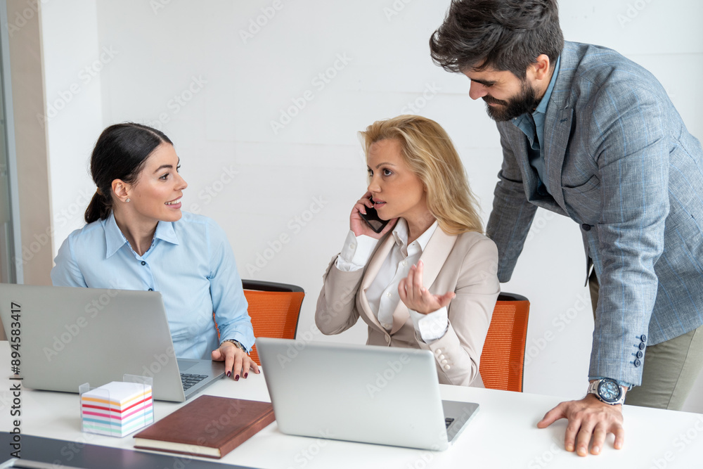 During a business meeting, blonde businesswoman talking to an investor on the phone and brainstorming ideas while her colleagues expecting positive news. During a business meeting, blonde businesswoman talking to an investor on the phone and brainstorming ideas while her colleagues expecting positive news.