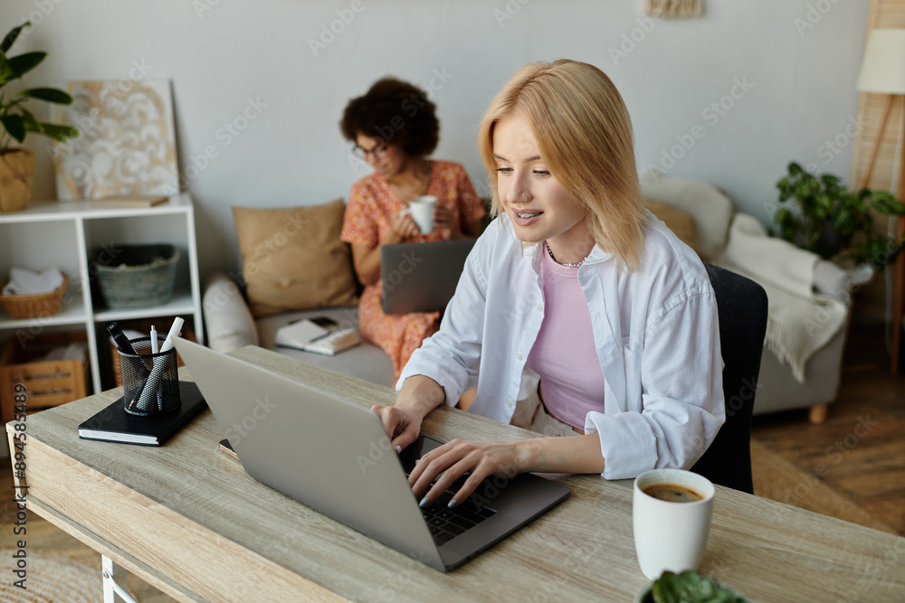 A lesbian couple enjoys a coffee break while working from home, focusing on their respective laptops. A lesbian couple enjoys a coffee break while working from home, focusing on their respective laptops.