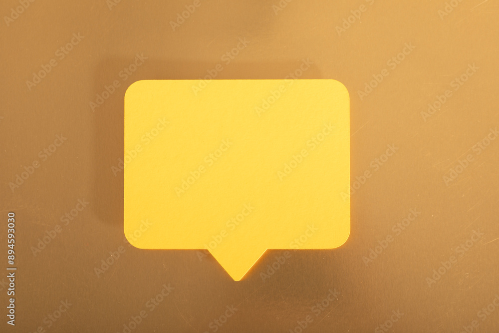 A yellow speech bubble sits on a brown surface A yellow speech bubble sits on a brown surface