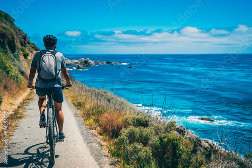 Man cycling along coastal path with scenic ocean view and clear blue sky