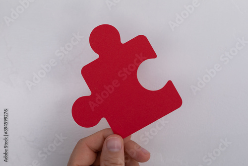 A hand holds a red puzzle p...