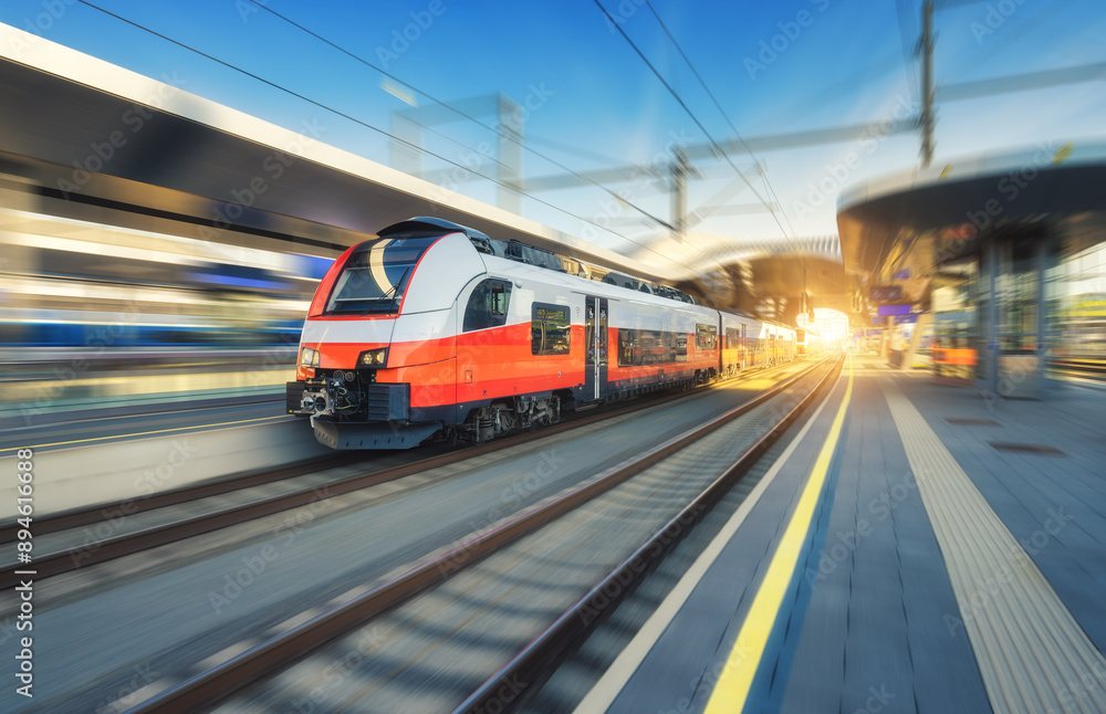 High-speed passenger train moving at railway station at sunset High-speed passenger train moving at railway station at sunset