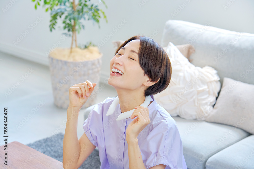リビングでアイスネックリングを使う女性 リビングでアイスネックリングを使う女性